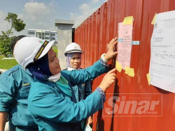 Kakitangan JAS Johor menampal notis di pagar kilang kitar semula sisa plastik.