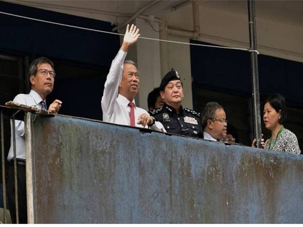 Menteri Dalam Negeri Tan Sri Muhyiddin Yassin (dua, kiri) melambai tangan ke arah penghuni Kompleks Perumahan Ibu Pejabat Polis Diraja Malaysia Kontinjen Sarawak ketika melawat kompleks perumahan berkenaan hari ini. - Foto Bernama 