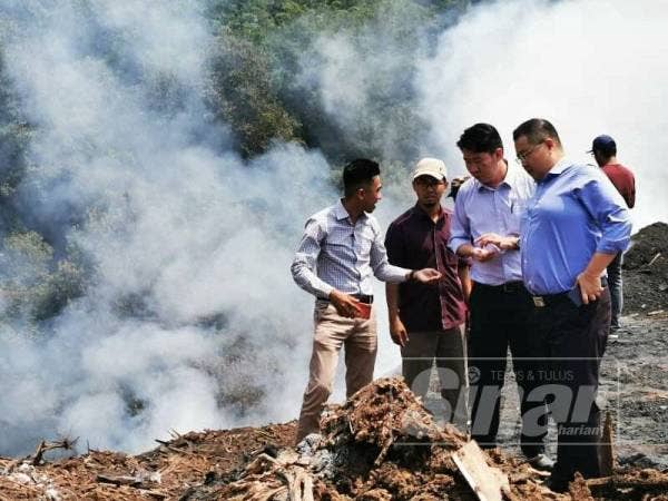 Simon Ooi (dua dari kanan) dan Robert Ling (kanan) membuat pemantauan di lokasi pembakaran terbuka.