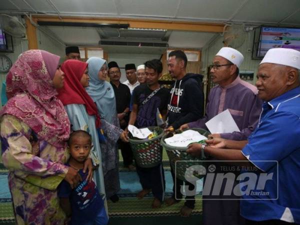 Abdul Rahim (dua dari kanan) beramah mesra selepas menyampaikan kutipan tabung bencana kepada sembilan mangsa kebakaran yang terlibat di Masjid Al-Falah, Sungai Isap 2, di sini hari ini.
