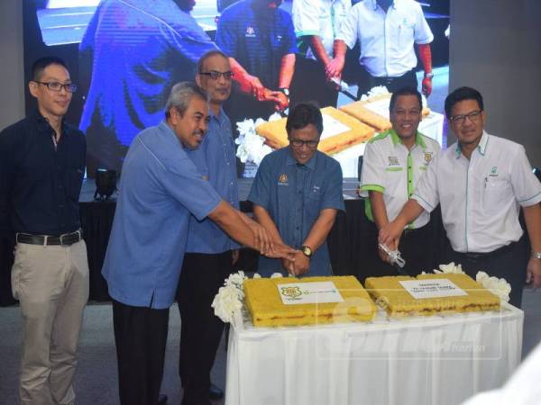 Mohd Roslan dan Omar memotong pulut kuning sebagai tanda kesyukuran pada majlis meraikan pencapaian BPPA beroperasi selama 20 tahun tanpa kemalangan di Mesra Mall Kemasik di Kemaman kelmarin.