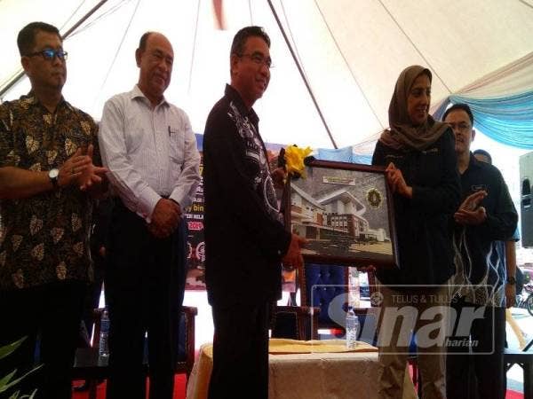 Latheefa (dua dari kanan) menyampaikan cenderahati kepada Adly selepas perasmian program Melaka Tolak Rasuah Peringkat negeri sempena Tahun Melawat Melaka 2019 di pekarangan Menara Taming Sari, Banda Hilir di sini hari ini.