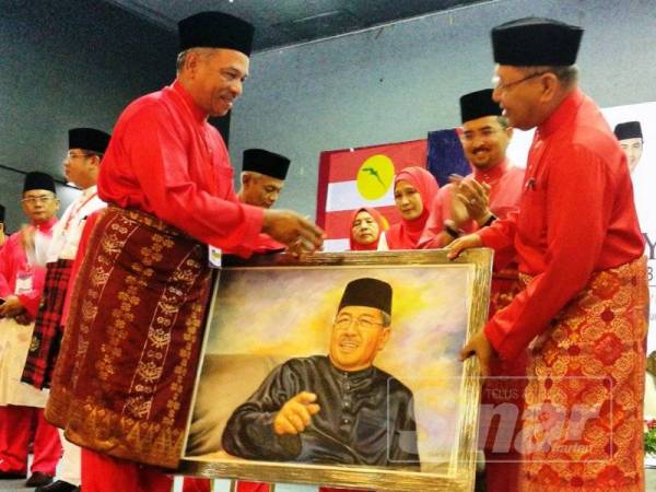 Mohd Yusof (kiri) menyerahkan anugerah khas dan gambar potret kepada Ahmad Bashah (kanan) sebagai penghargaan atas sumbangan beliau terhadap UMNO Kedah sambil disaksikan Dr Asyraf Wajdi (tengah).