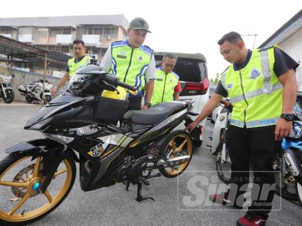 Nasyrul Ridzuan (kiri) melihat antara motosikal yang disita selepas didapati diubah suai bagi kegiatan lumba haram.