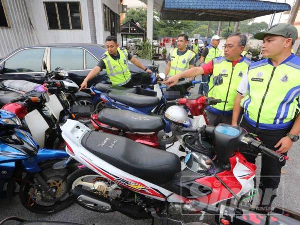 Nasyrul Ridzuan (kanan) memeriksa motosikal yang disita dalam Op Samseng Jalanan sekitar Ipoh hari ini.