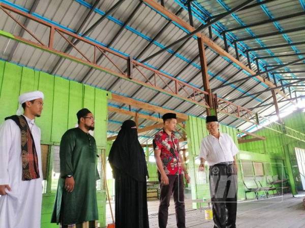 Nordin (kanan) bersama Mohd Khairul Amin (dua kanan) meninjau pembinaan bumbung Madrasah Qiraati Ar-Rahmaniah Kampung Geting.