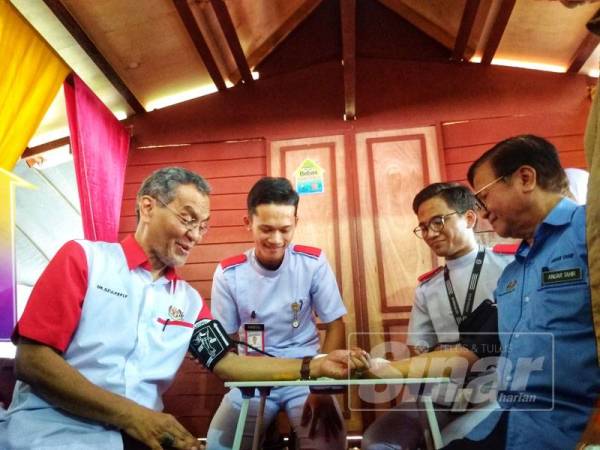 Dzulkifley (kiri) dan Mohd Anuar melakukan pemeriksaan tekanan darah simbolik perasmian program tersebut, di sini hari ini.
