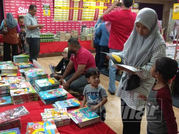Seorang pengunjung sedang memilih bahan bacaan bersesuaian untuk anak-anaknya.