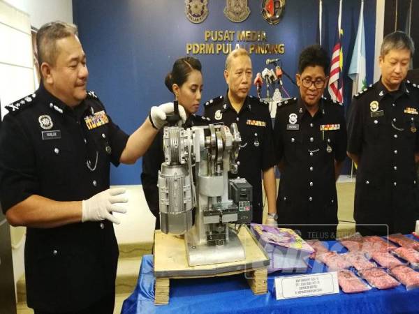 Roslee (kiri) menunjukkan mesin yang digunakan suspek untuk memproses dadah.