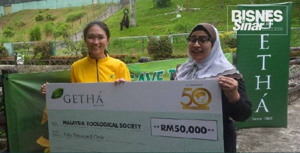Amelia (kiri) menyerahkan replika cek kepada Linda sebagai simbolik penyerahan sumbangan dalam usaha membantu pemuliharaan orang utan di Zoo Negara di Ampang, Selangor petang semalam.