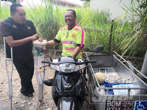Mohd Kufri (kiri) menyampaikan tongkat kepada rakan senasib, Abdul Razak yang mengusahakan perniagaan ais krim bergerak di sini semalam.
