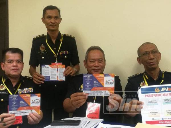 Mohamad (kanan) menunjukkan manual penggunaan aplikasi JPJeBid untuk memudahkan orang ramai membida nombor pendaftaran kenderaan.