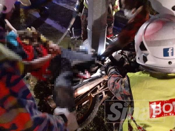 Anggota bomba mengeluarkan mangsa yang tersepit selepas motosikal ditunggangnya merempuh tiang lampu dalam kejadian di Jalan Slim Lama-Tanjung Malim malam tadi.