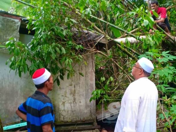 Mohd Rodzi (kanan) menziarahi mangsa ribut di Kampung Changgai semalam.

