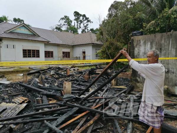 Jaafar menunjukkan kayu yang di simpan di bawah rumah Ismail hangus terbakar. 