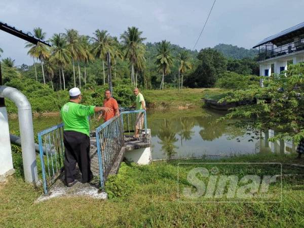 Mohd Rodzi (kiri) meninjau empangan Sungai Yong bagi memastikan enjin pengepam berfungsi dengan baik.