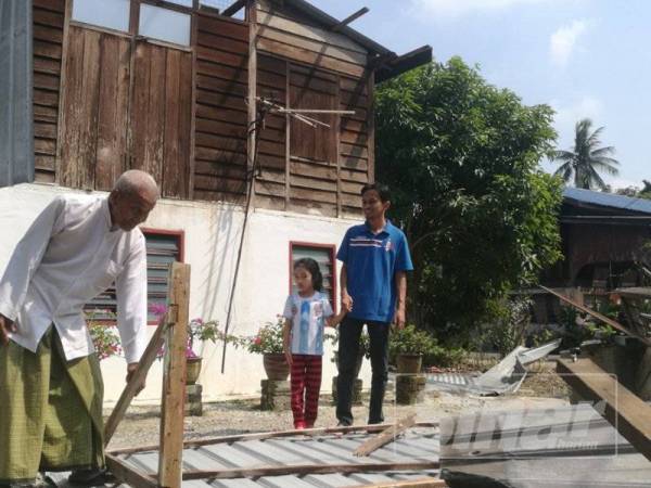 Ibrahim bersama menantu serta cucunya melihat sisa zink bumbung dan dan kayu yang berselerak di halaman rumahnya.