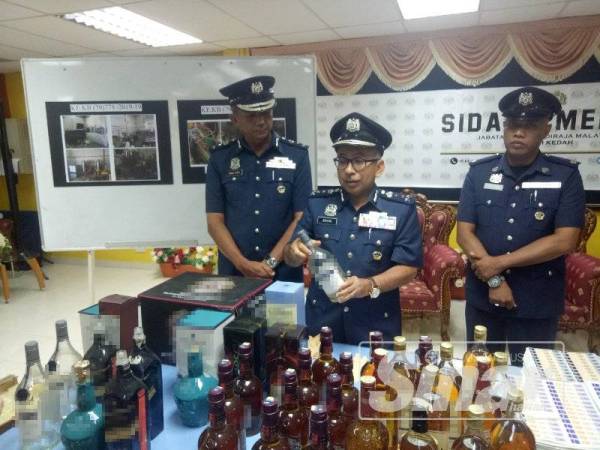 Johari (tengah) menunjukkan botol minuman keras kosong yang dirampas anggotanya dalam serbuan terbabit.