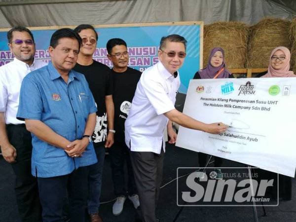 Salahuddin menandatangani plak perasmian kilang susu milik The Holstein Milk Company disaksikan Dr Quaza Nizamudin, Loi Tuan Ee dan Azmi.