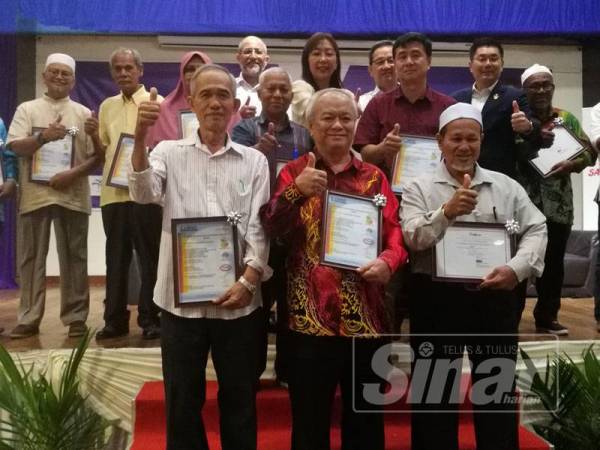 Teresa (belakang, lima, kiri) menyerahkan sijil MSPO kepada 15 pekebun sawit daerah Perak di Taiping hari ini.