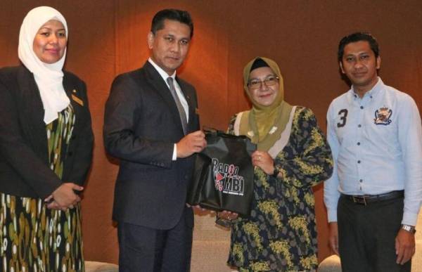 Saidatul Akma (dua dari kanan) menyampaikan cenderahati kepada Gerard pada sidang media berkenaan.