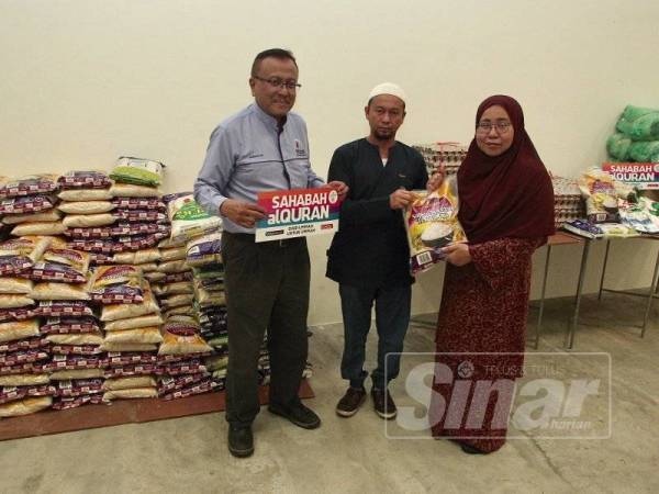 Azman (kiri) bersama Marhaini member sumbangan barangan asas kepada Saifulizam Mohamad (tengah) dalam membantu meringankan beban kakitangan Utusan Malaysia di ibu pejabat Utusan Melayu. - FOTO ZAHID IZZANI