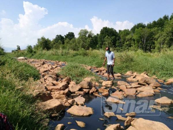 Salah seorang penduduk kampung meninjau keadaan air yang mengalir masuk ke Sungai Daing.