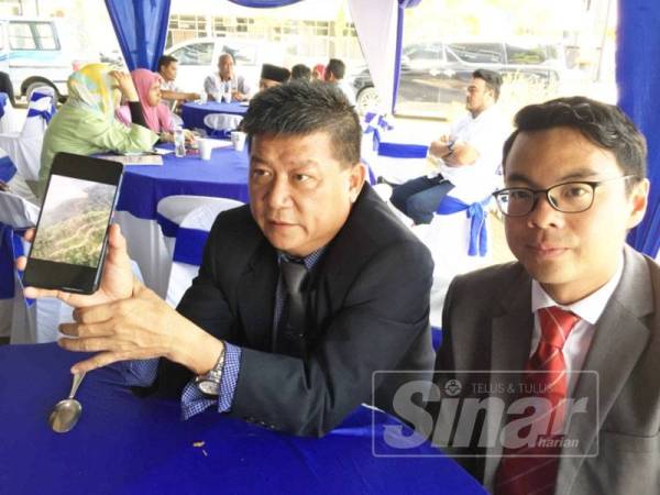 Chon Siang (kiri) dan Chean Chung (kanan) menunjukkan gambar mengenai penerokaan hutan simpan di Sungai Lembing yang diambil olehnya semasa melakukan tinjauan udara Julai lalu.