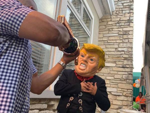 Seorang lelaki memakai topeng Presiden Trump memegang dada seolah-olah ditembak dalam satu acara mengumpul dana politik di pinggir Winfield pada Jumaat lalu.