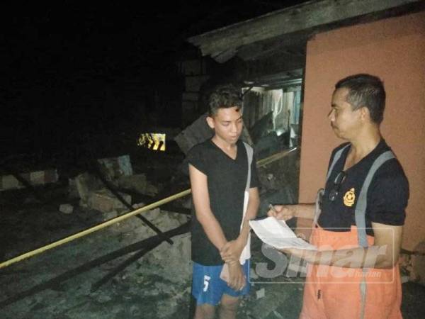 Mahusin Hassan (kanan) sedang mendapatkan maklumat daripada Aliah Ismail (kiri) di tapak kebakaran di Kampung Tebing Tinggi, Sabak.