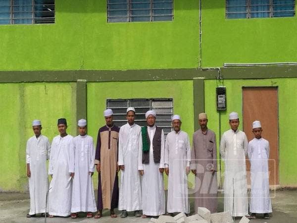Mohd Nawawi (tengah) bersama sebahagian guru dan pelajar Pusat Pengajian Ulum Arabiah Kampung Sungai Darak.