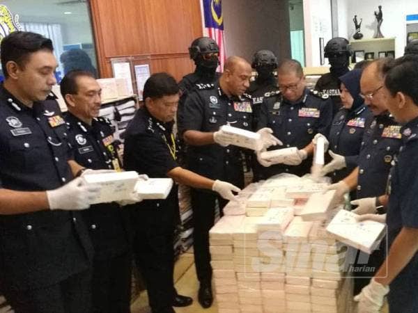 Paddy (tengah) dan Mohd Khalil (empat dari kiri) melihat antara bungkusan dadah dirampas selepas sidang media, hari ini.