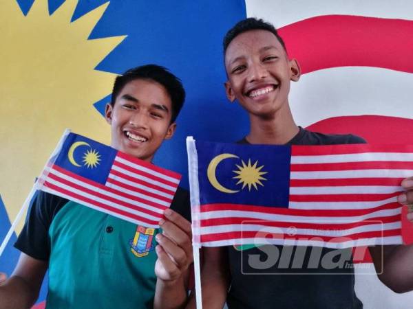 Ashraf Fahimi (kiri) bersama rakannya memegang Jalur Gemilang.