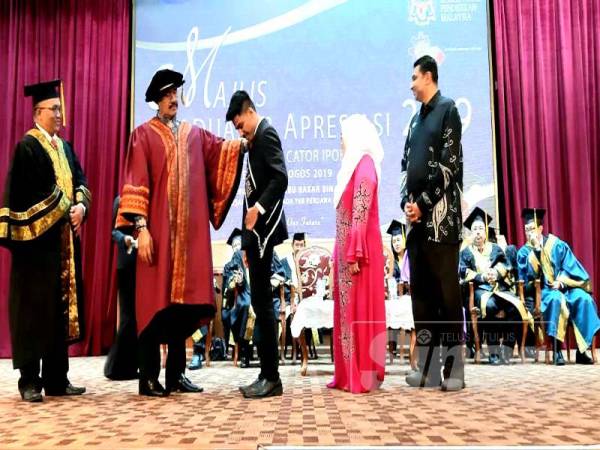 Abu Bakar (dua dari kiri) membetulkan selempang yang dipakai Nasraan Shah Mohamed Naseer yang diumumkan sebagai penerima Anugerah Emas sempena Majlis Graduasi & Apresiasi Kolej Vokasional Lebuh Cator 2019, di sini hari ini.
