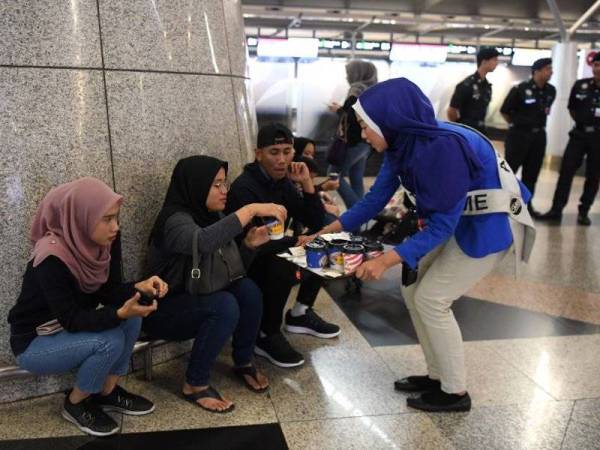 Airport Care Ambassadors Malaysia Airport Raja Intan Umairah Raja Ikram (kanan) memberi minuman panas kopi dan teh kepada para penumpang sehingga 10 pagi tadi di KLIA berikutan gangguan sistem yang semakin beransur pulih. - Foto BERNAMA