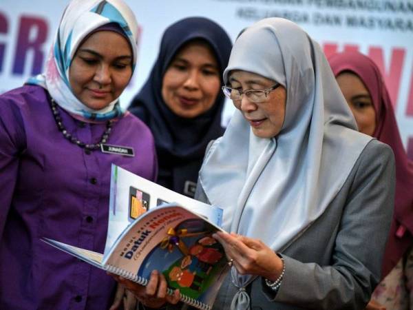 Dr Wan Azizah (kanan) melihat buku Modul Keibubapaan Datuk Nenek sempena Program Santuni Rakyat Peringkat Negeri Kedah anjuran Lembaga Penduduk dan Pembangunan Keluarga Negara (LPPKN) hari ini. - Foto Bernama