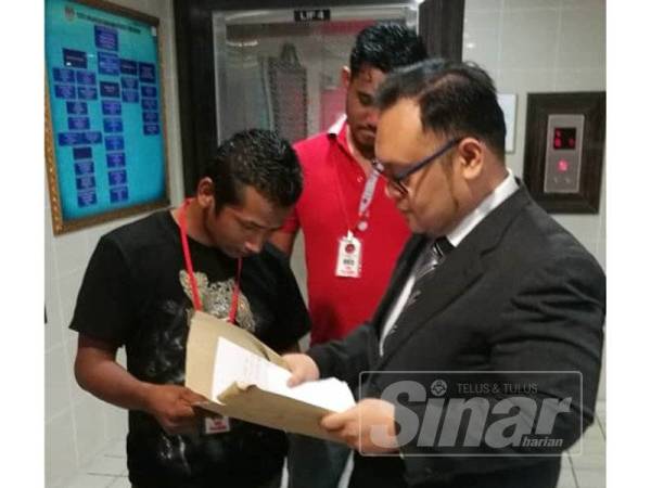 Md Zawawi (kiri) berbincang sesuatu dengan peguamnya, Mohd Hayatuddin (kanan) di luar kamar mahkamah.