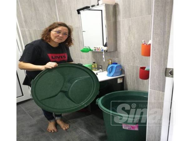 Kim Pin menunjukkan air yang disimpan di rumahnya.