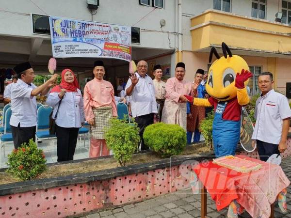 Azrul Mahathir bersalaman dengan maskot Combee ketika merasmikan sambutan ambang merdeka di SKSB semalam.