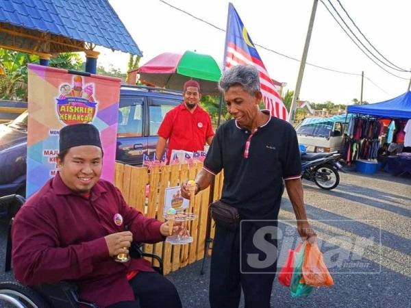 Salah seorang pengunjung Pasar Malam Lanchang menerima aiskrim percuma daripada Abdul Rahman.