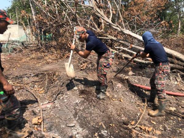 Anggota bomba menggali parit bagi menyalurkan air di sekeliling kawasan yang terbakar bagi mengelakkan kebakaran terus merebak.- Foto: JBPM JOHOR
