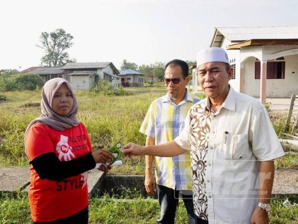 Wan Hapandi menyerahkan bantuan segera berbentuk eang tunai kepada Aslinda.