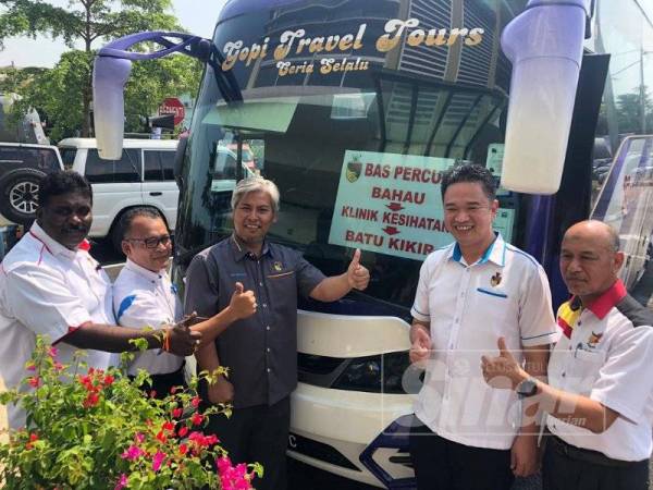 Kok Seong (dua dari kanan) di hadapan bas yang menawarkan perkhidmatan percuma kepada penduduk di Bahau, Jempol.
