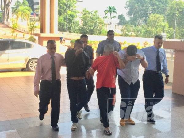 Ahmad Ghazali (dua dari kiri) dan Hamdan (tengah) dihadapkan ke Mahkamah Majistret Kuantan hari ini atas tuduhan menipu pengusaha bauksit empat tahun lalu.