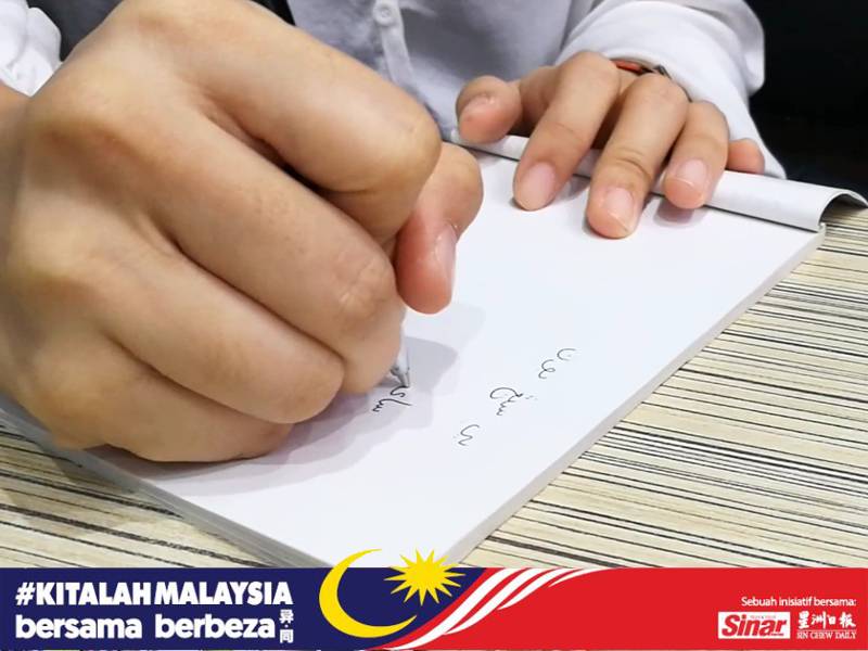 Lauren menunjukkan kemahiran menulis jawi.