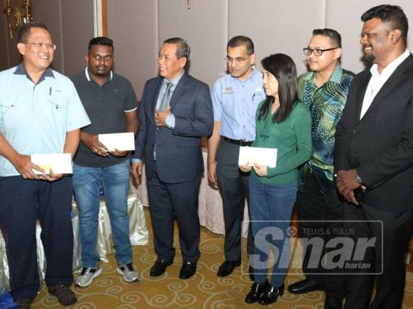 Aminuddin (tiga dari kiri) dan Mohammed Azman (tengah) beramah mesra dengan penerima caruman Perkeso di Klana Resort hari ini.