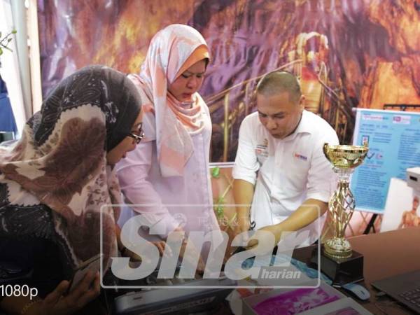 AHMAD Hamdi (kanan) menerangkan sesuatu kepada Menteri Pembangunan Luar Bandar, Datuk Seri Rina Mohd Harun ketika kunjungan reruai GiatMara.