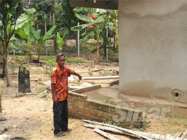 Mohd Sidek menunjukkan kesan paras air banjir di rumah penduduk.