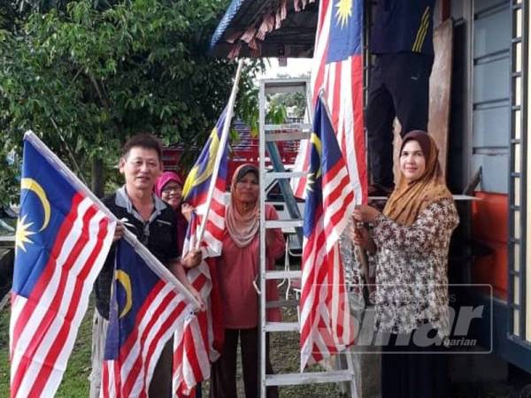 Ahli KRT Yan bekerjasama memasang Jalur Gemilang.
