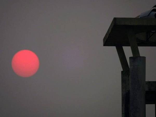 Matahari berwarna kemerahan ketika cuaca berjerebu yang dirakam berhampiran Taman Negara Wetlands di Samariang, Petra Jaya hari ini. -Foto Bernama
